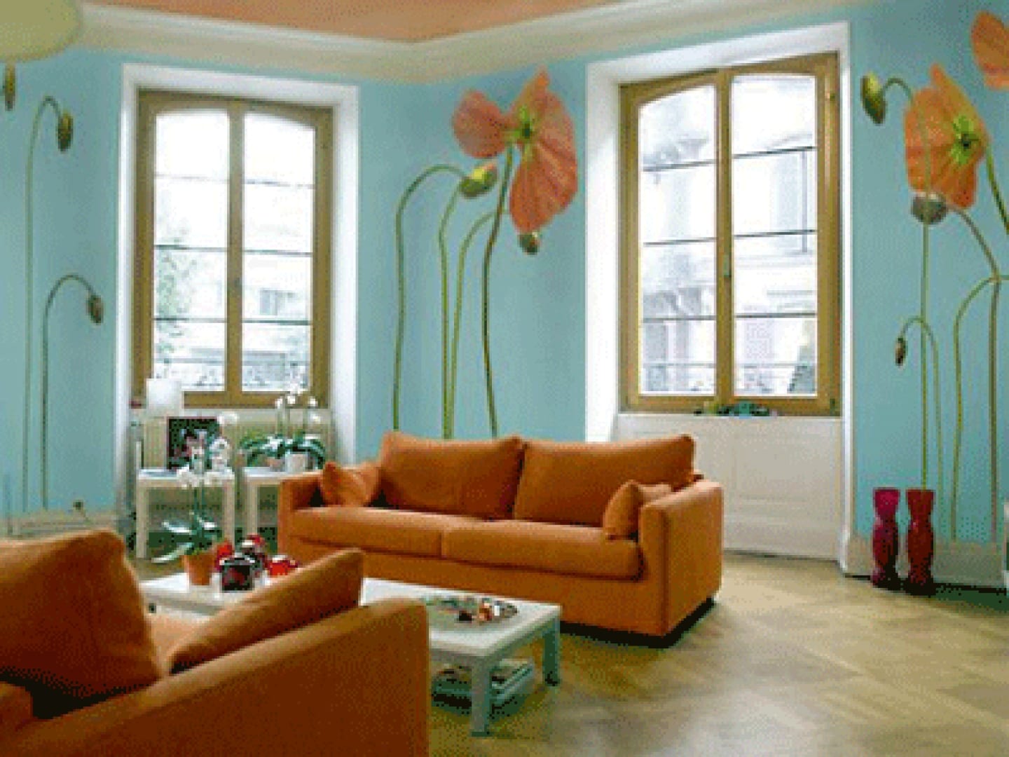 Wohnzimmereinrichtung in blau mit Sofa in orange und Mohnblumen-Wanddeko
