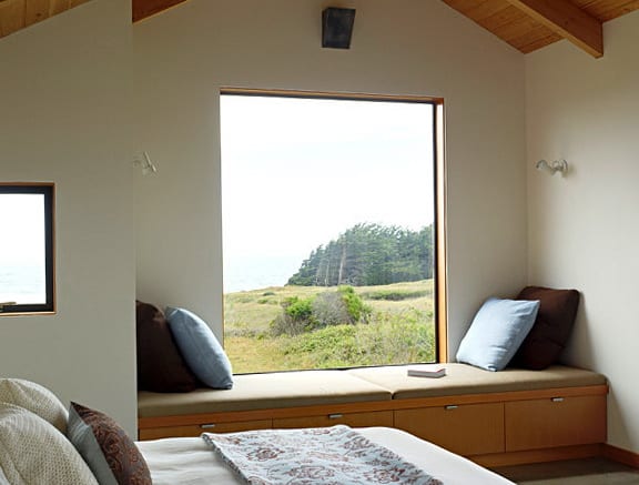 modernes schlafzimmer mit panoramafenster und sitzbank aus holz mit kissen dekorieren