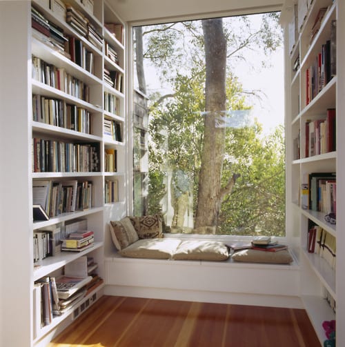 kleiner bibliothek mit weißen Bücherregalen und Panoramafenster mit weißer Fensterbank