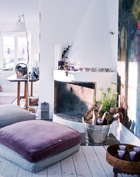 mein wohnzimmer mit rustikalem kamiöfen und lila bodenkissen