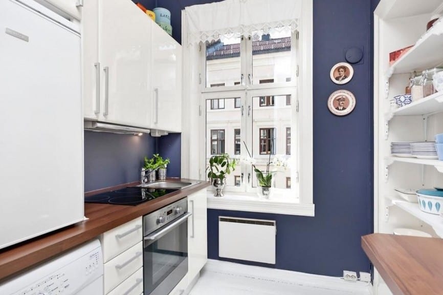 kleines appartement mit weißer küche und wandfarbe blau-küchenschränke weiß und küchenarbeitsplatte aus holz