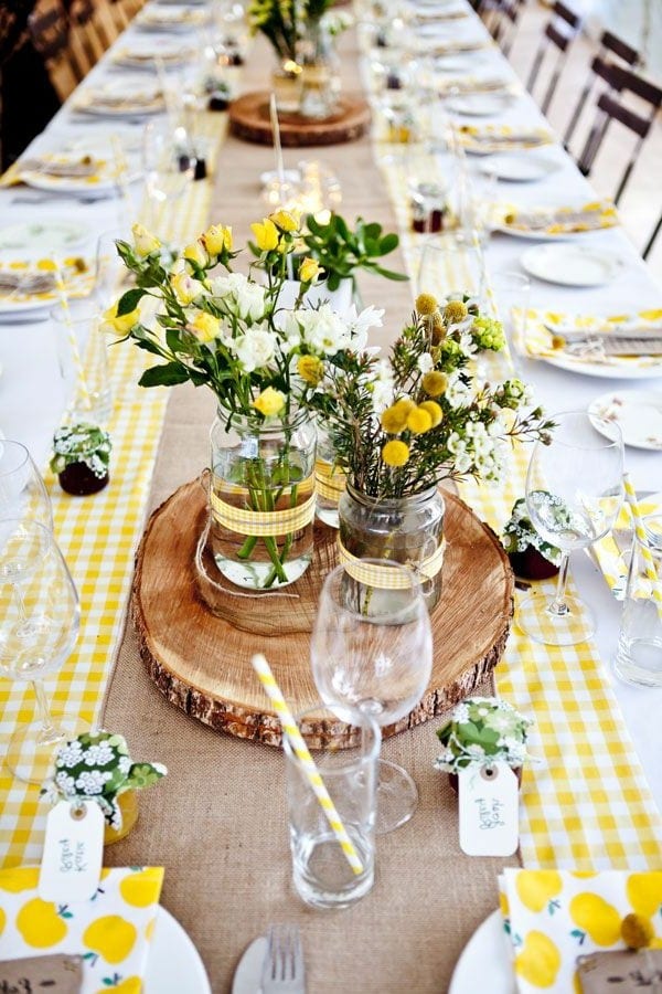 tischdeko in gelb mit runden Holzgestellen und Blumen in weiß und gelb