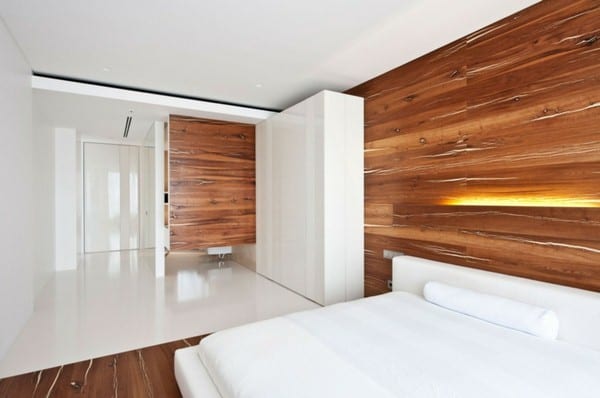 moderne schlafzimmer mit bett und kleiderschrank in weiß und wandgestaltung mit holz und wandleuchte für indirekte beleuchtung schlafzimmer