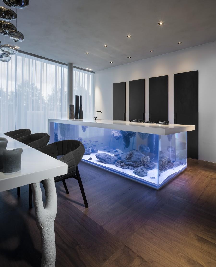 minimalistische küche einrichten mit moderner kochinsel-aquarium und Designer-Esstisch weiß mit schwarzen Armsesseln und coole Wanddekoration küche mit eingebauten Küchenschränken