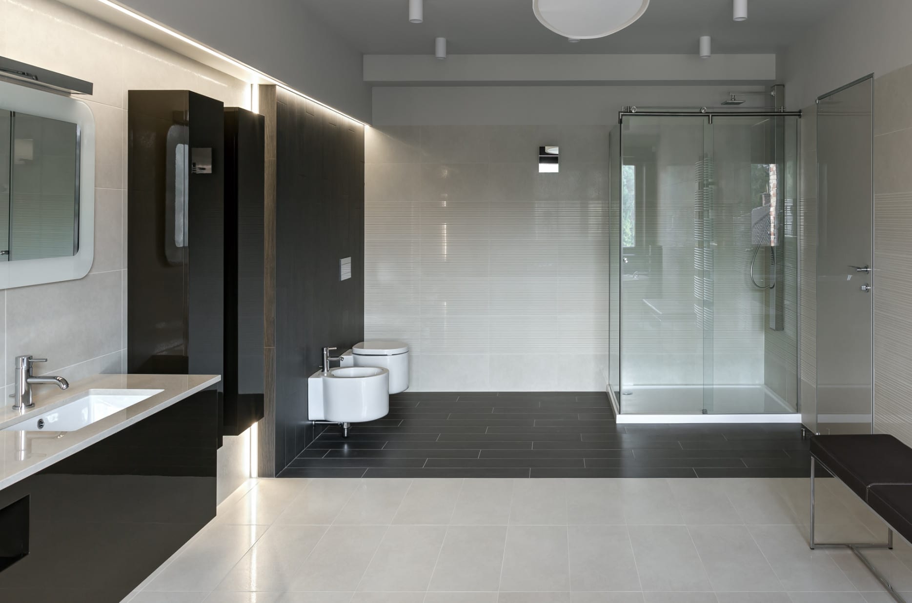 modernes bad mit schwarzen und weißen badfliesen, waschtisch und wandschränke in hochglanz schwarz und einbaudeckenleuchte