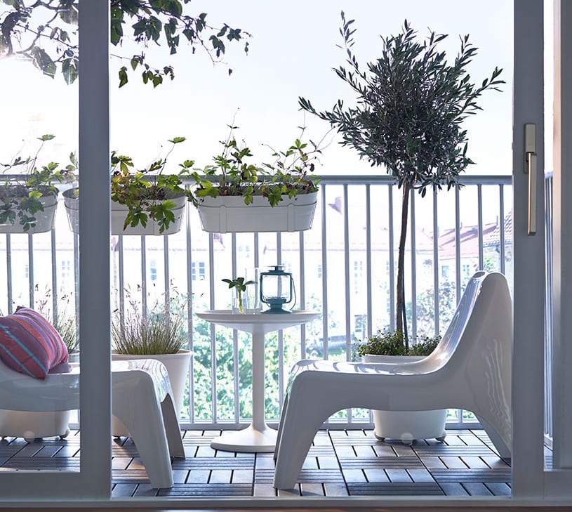 kleiner balkon modern einrichten in weiß mit holzfliesen und weißen blumentöpfen auf rollen