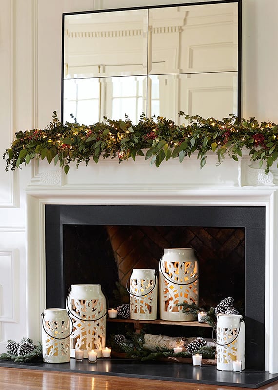 kamin modern und weihnachtlich dekorieren mit rechteckigem spiegel im schwarzen rahmen, weißen laternen rund und gerlande aus grünen blättern und lichterkette